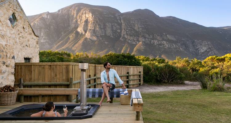 A couple relaxing outdoors in a hot tub with mountain views.