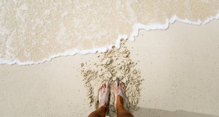 Pieds dans le sable avec les vagues de l'océan sur une plage.