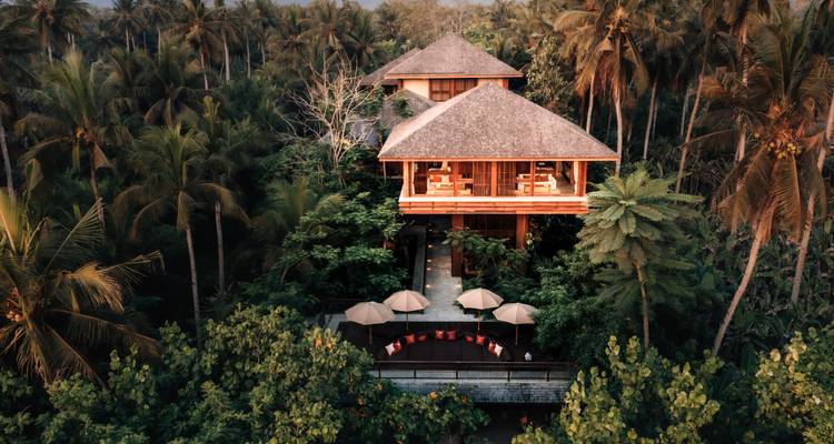 Vue aérienne d'un complexe hôtelier de luxe au milieu d'une végétation tropicale dense.