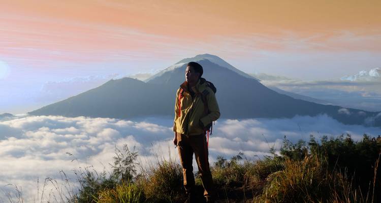 Personne profitant de la vue sur les montagnes au milieu des nuages au lever du soleil.