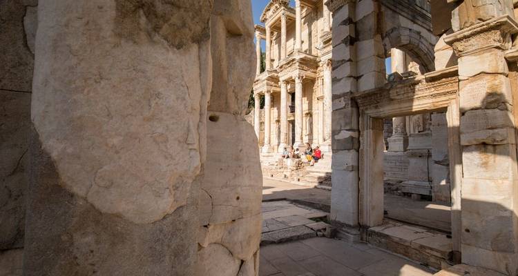 Tourists exploring ancient ruins with large stone blocks.
