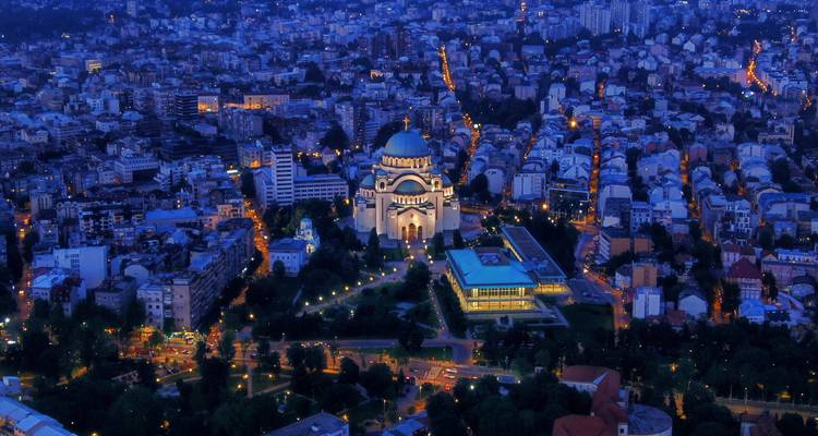Aerial view of a city with a large church lit up at night.