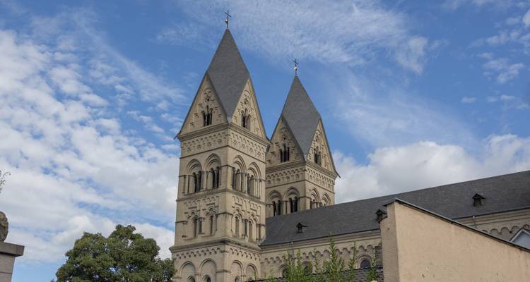 Historic church with two pointed towers against a backdrop of cloudy sky.