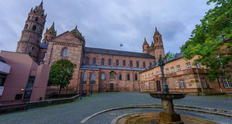 Stone Romanesque Worms Cathedral towering over a quiet cobbled square with a fountain.