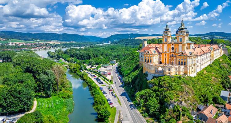 La Abadía de Melk encaramada en un acantilado sobre el Danubio con exuberante campiña y nubes dramáticas