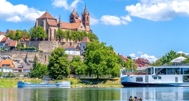 Vista de una iglesia en una colina con un río y un barco en primer plano.