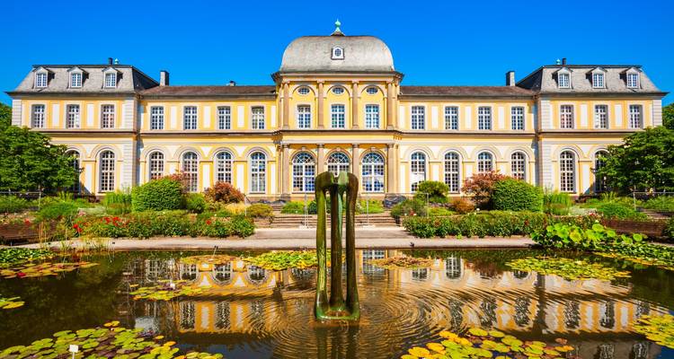 Élégant palais avec un bassin et une fontaine reflétant le bâtiment.