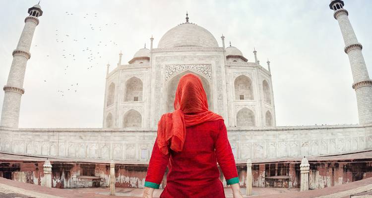 Persoon gekleed in het rood bij de Taj Mahal.