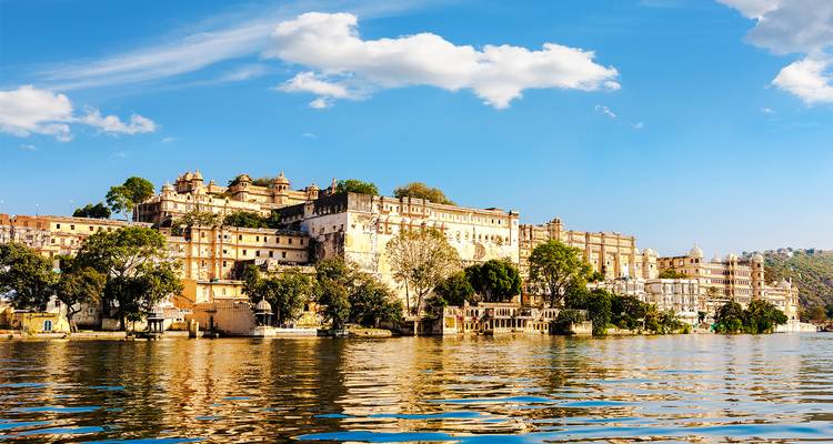 Stadsgezicht van Udaipur met gebouwen langs de waterkant en reflecties in het meer.
