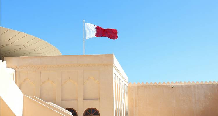 Gebouw met Qatarese vlag tegen een heldere blauwe hemel.