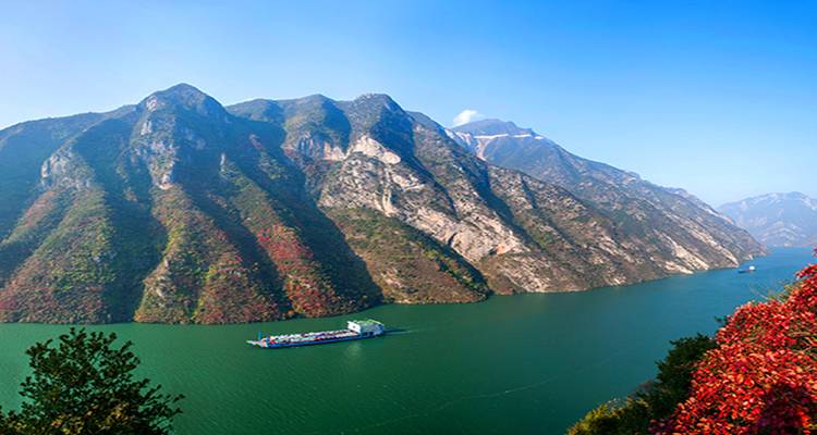 Péniche sur une rivière pittoresque bordée de falaises escarpées.