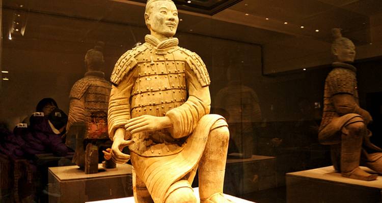 Statue de guerrier en terre cuite dans un cadre muséal.