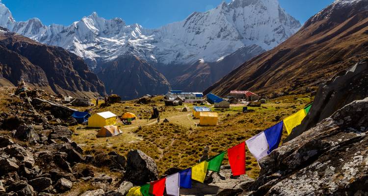 Bunte Zelte und Gebetsfahnen mit der Annapurna-Bergkette im Hintergrund.