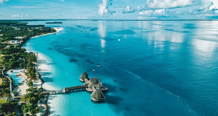 Vista aérea de una costa prístina con bungalows sobre el agua.