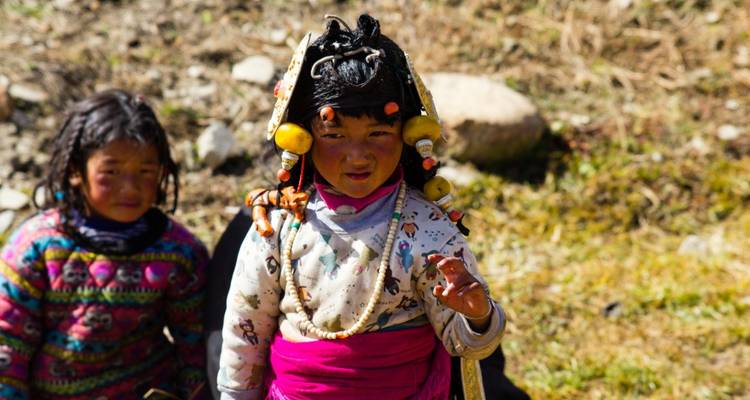 Two children in traditional clothing outdoors.