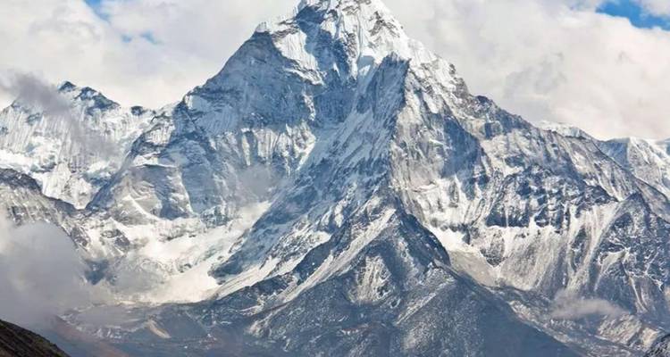 Majestic snowy mountain under a partly cloudy sky.