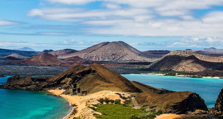 Vista panorámica del paisaje volcánico de la Isla Bartolomé con playa dorada, agua turquesa y conos escarpados bajo nubes dispersas.