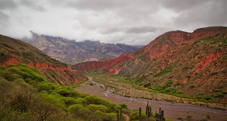 Dramatische Landschaft mit roten Hügeln und einem Flussbett.