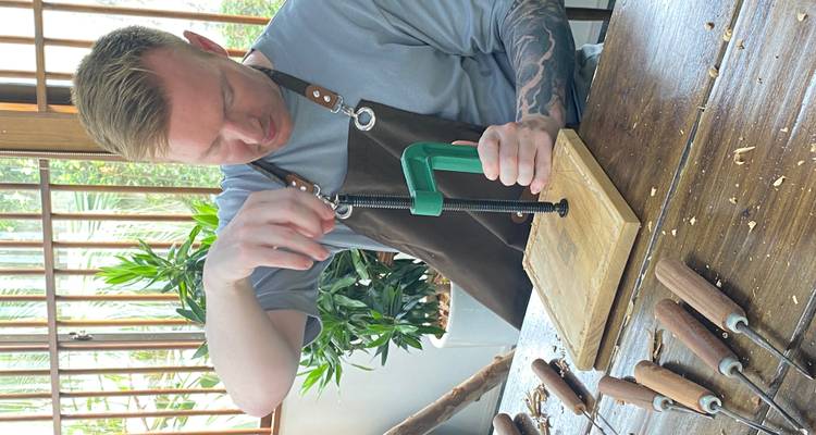 Man using a woodworking press on a table indoors.