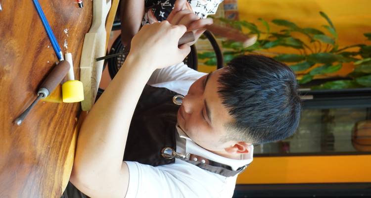 Man concentrating on wood carving at a table.