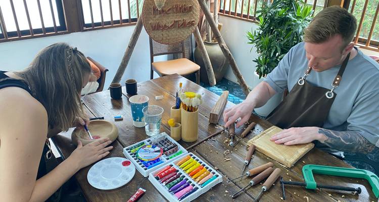 A man and a woman at a table engaged in woodworking and crafting.