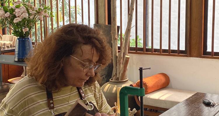 Woman with curly hair using a woodworking tool on a table.