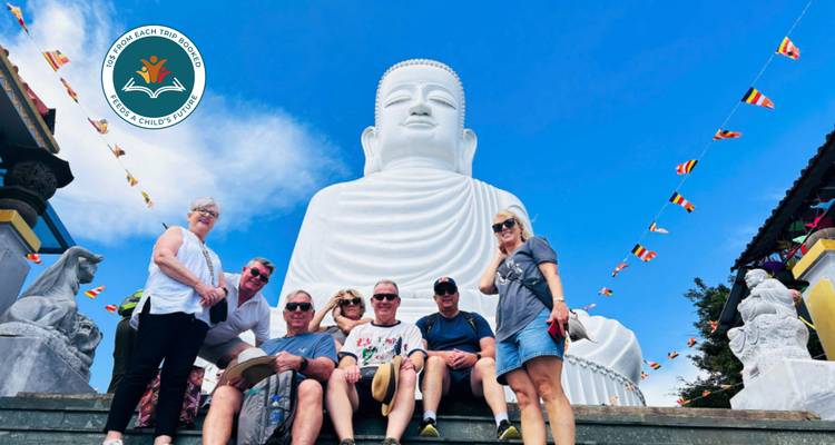 Groep poseert voor een groot Boeddhabeeld met een watermerk.