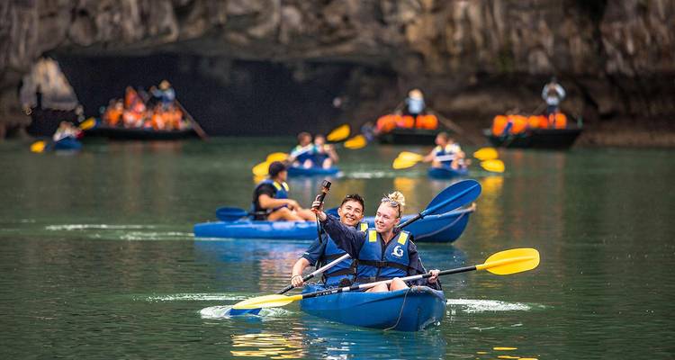 Kajakkers die peddelen door een grotingang.