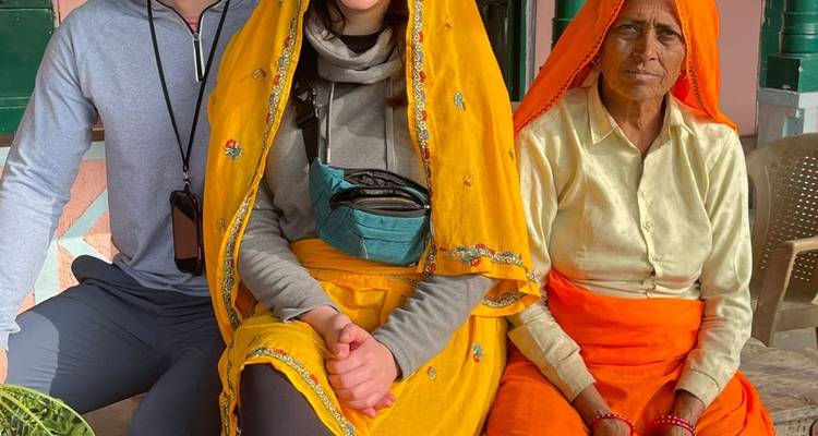Tres personas sentadas juntas, dos vistiendo ropa tradicional.
