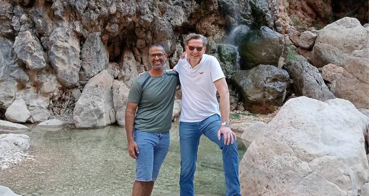 Deux hommes posant devant une petite cascade.