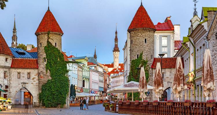 Straßenansicht alter Gebäude im europäischen Stil mit einem Turm im Hintergrund.