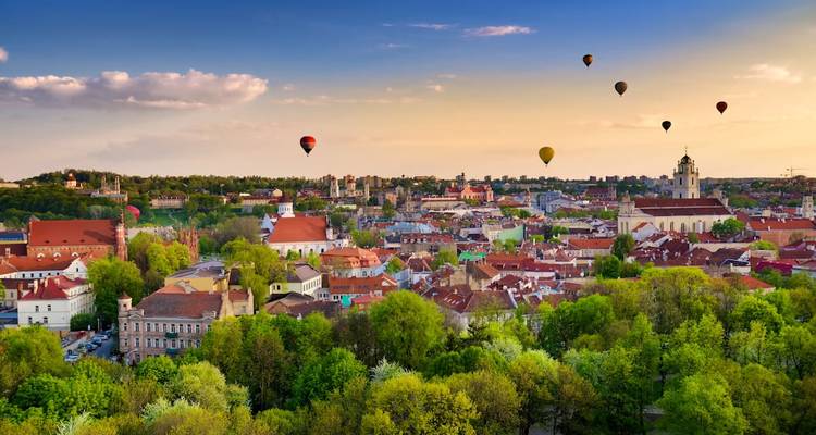 Luftaufnahme einer Stadtlandschaft mit Heißluftballons am Himmel.