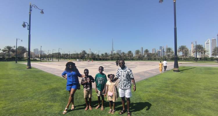 Famille posant sur une pelouse verte avec l'horizon urbain en arrière-plan.