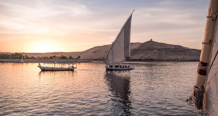 Bateaux à voiles traditionnels sur une rivière au coucher du soleil, une vue pittoresque.