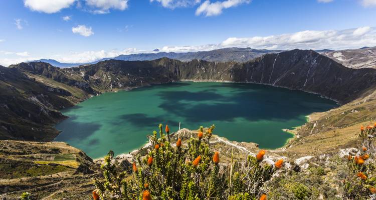 Volcanic crater lake with vibrant water and surrounding mountains.