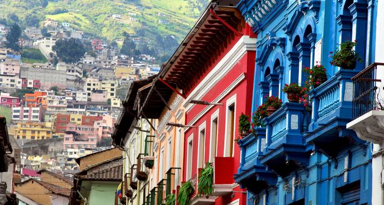 Colorful historic buildings lining a street with a hilly backdrop.
