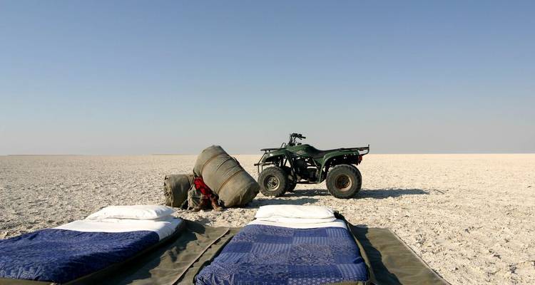 Two beds and a quad bike in an open barren landscape.