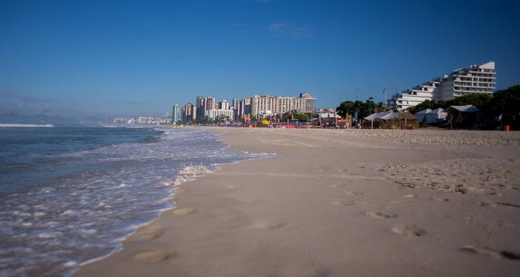Beachfront buildings with white sand and waves in Rio de Janeiro.