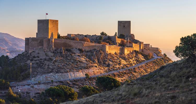 Ancient castle on a hill with sunset lighting highlighting its walls.