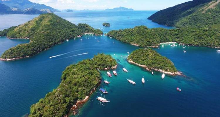 Vue aérienne d'îles tropicales et de bateaux dans une eau bleue claire.