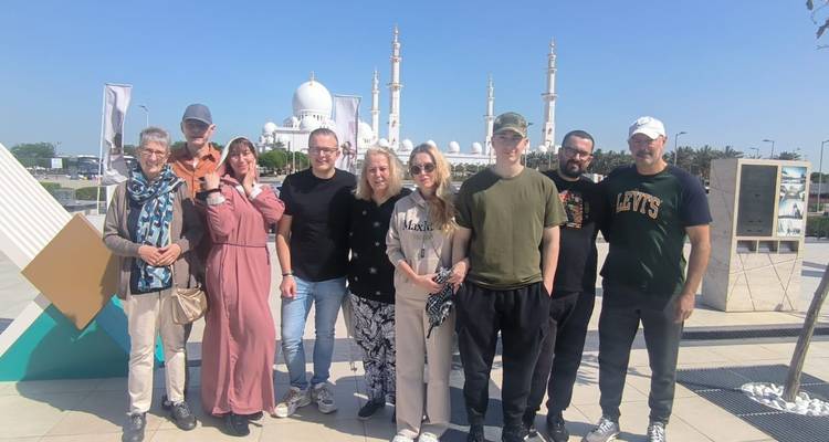 Groupe posant devant une mosquée sous un ciel bleu.