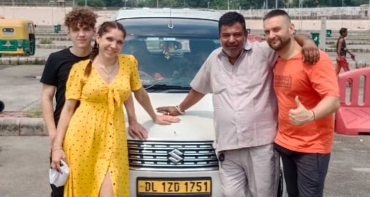 Eine Gruppe, die vor einem Fahrzeug mit sichtbarem Kennzeichen posiert.