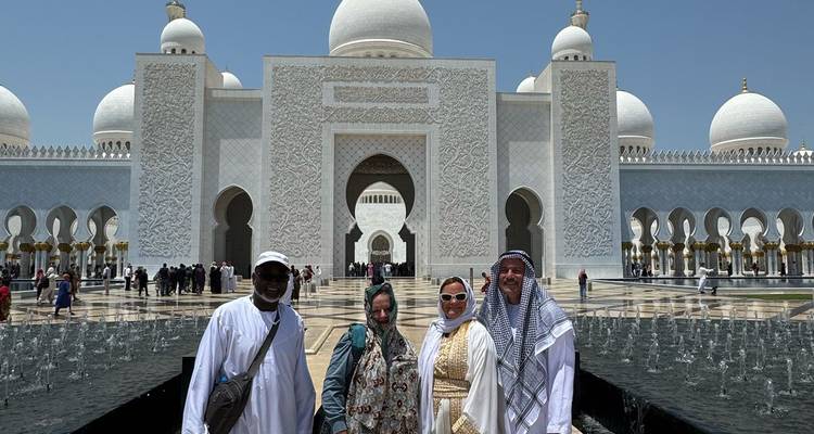 Quatre personnes debout devant l'entrée d'une mosquée blanche.