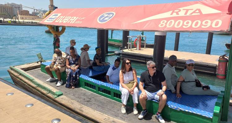 Des gens sur un petit ferry sur l'eau, avec des bâtiments de la ville en arrière-plan.
