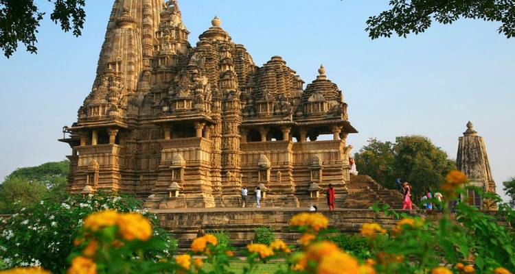 Temple de Khajuraho avec des plantes fleuries au premier plan.