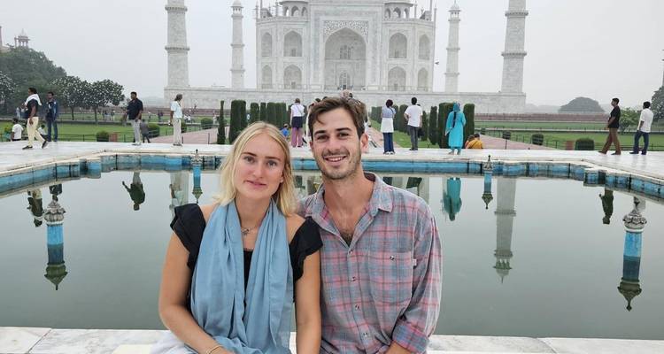 Ein Paar posiert vor der symmetrischen Schönheit des Taj Mahal.