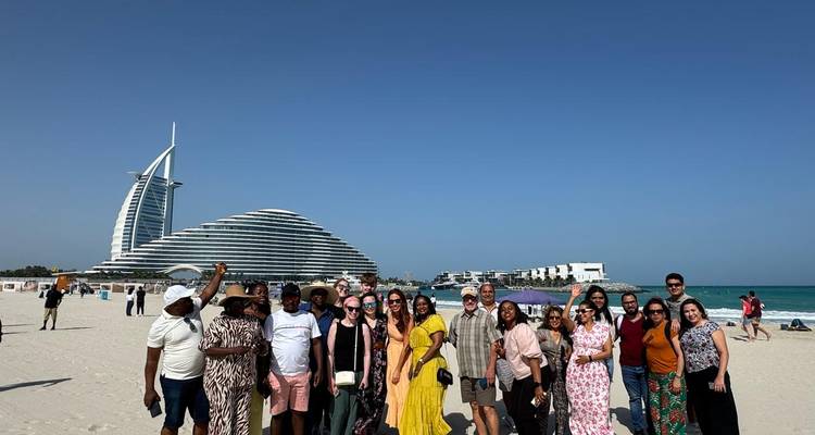 Grand groupe de personnes sur une plage avec des bâtiments modernes emblématiques.