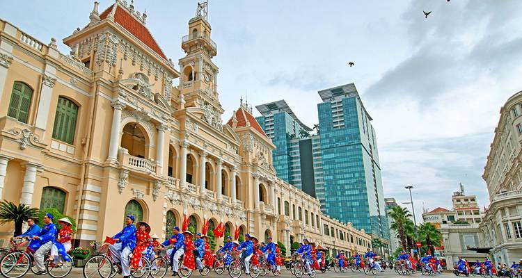 Cyclistes en costumes traditionnels devant un bâtiment historique.