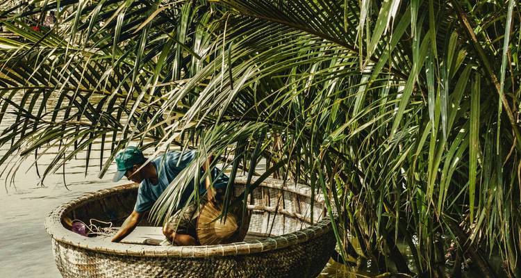 Deux personnes dans un bateau-panier entourées d'une végétation luxuriante.