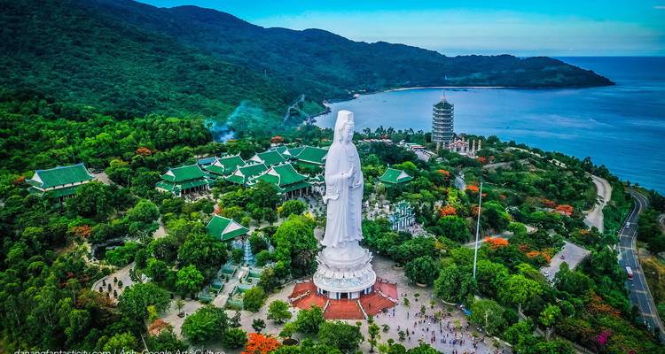 Vue aérienne d'une grande statue blanche et d'un complexe de temples au bord de la mer.